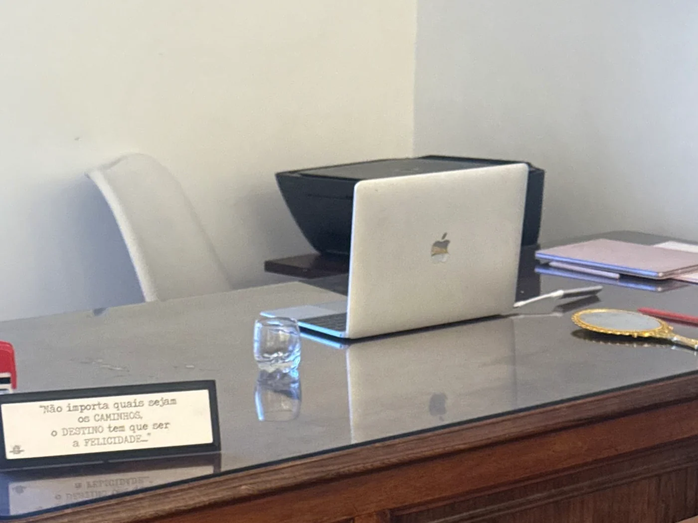 Mesa de trabalho da clínica, com a placa emoldurada sobre a felicidade